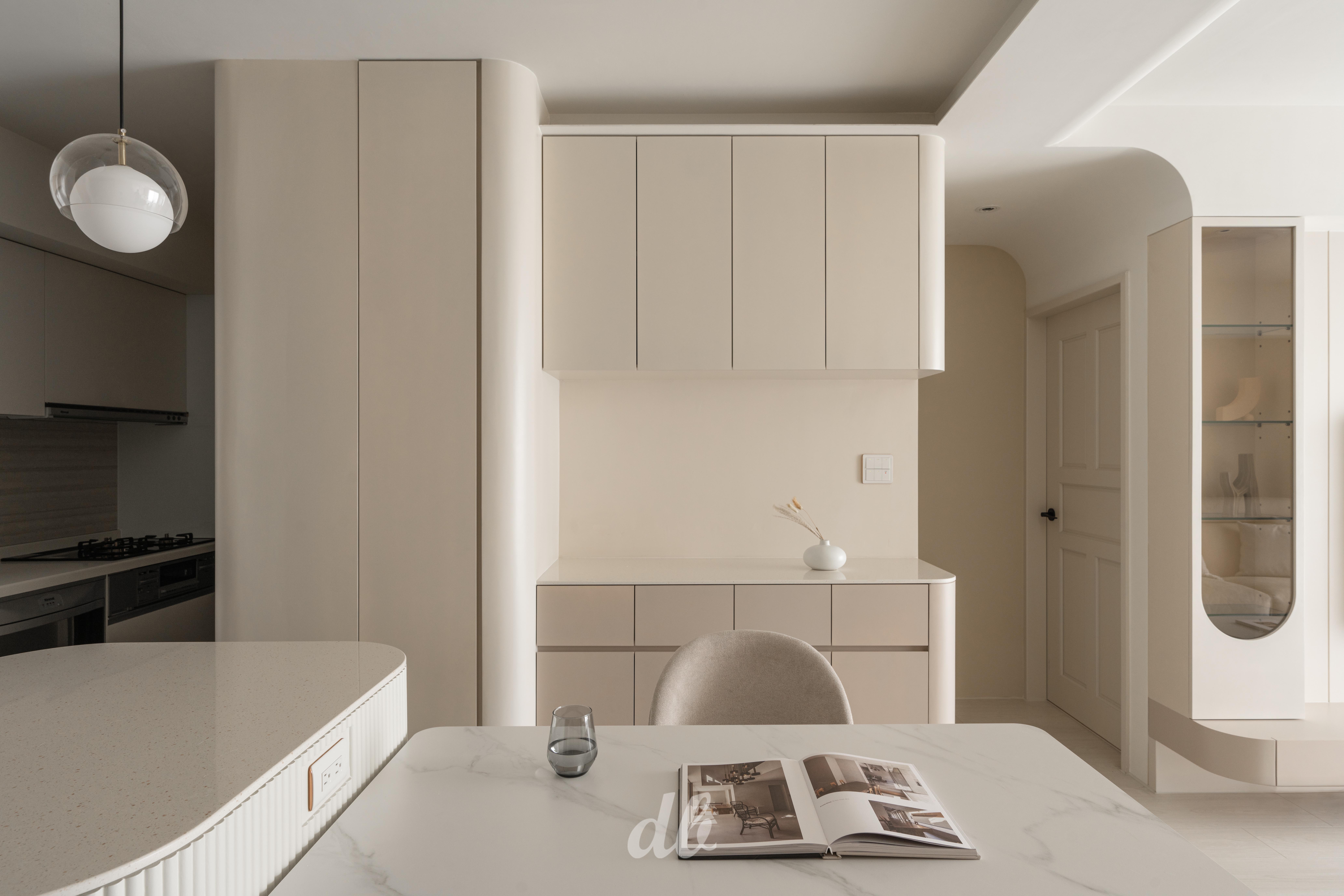 韓式奶油風餐廚日造設計案例：奶油色系的圓弧導角收納櫃牆與中島吧台，搭配造型格柵裝飾與輕奢大理石紋餐桌，透過高明度低飽和的色調、圓潤線條與自然材質運用，營造出溫暖柔和且充滿韓系美學的居家氛圍。