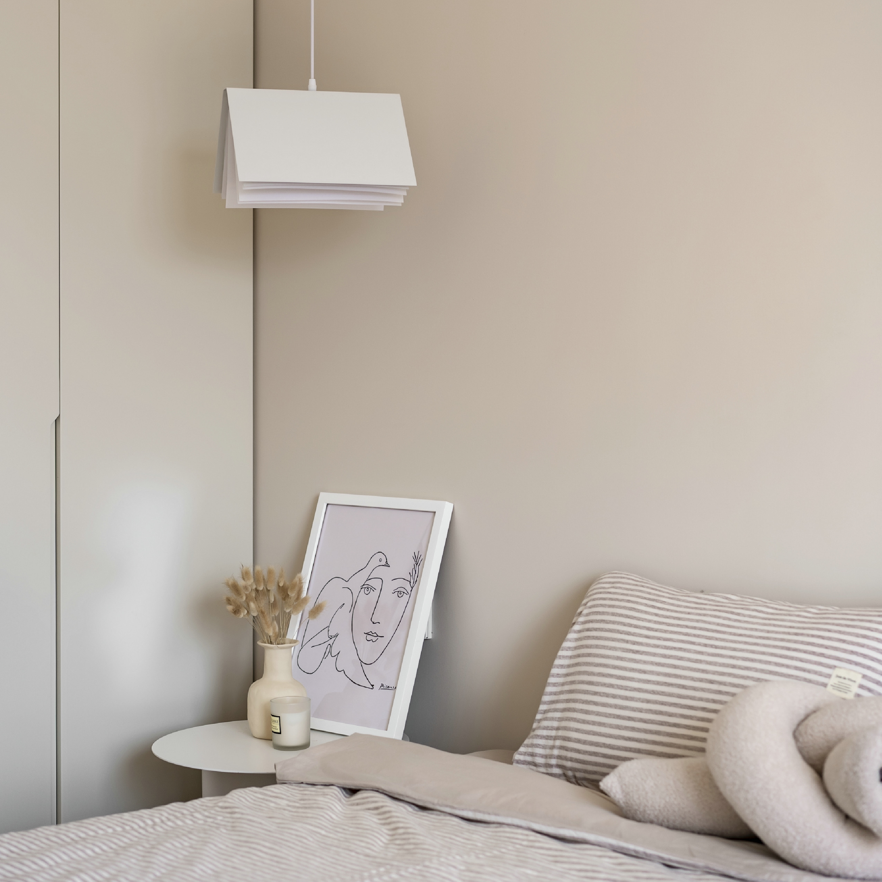 韓式奶油風臥室提案：暖杏色牆面與自然材質床寢，搭配造型吊燈與極簡藝術畫作，運用低飽和色彩與圓潤線條打造溫潤、具藝術感的日常角落。