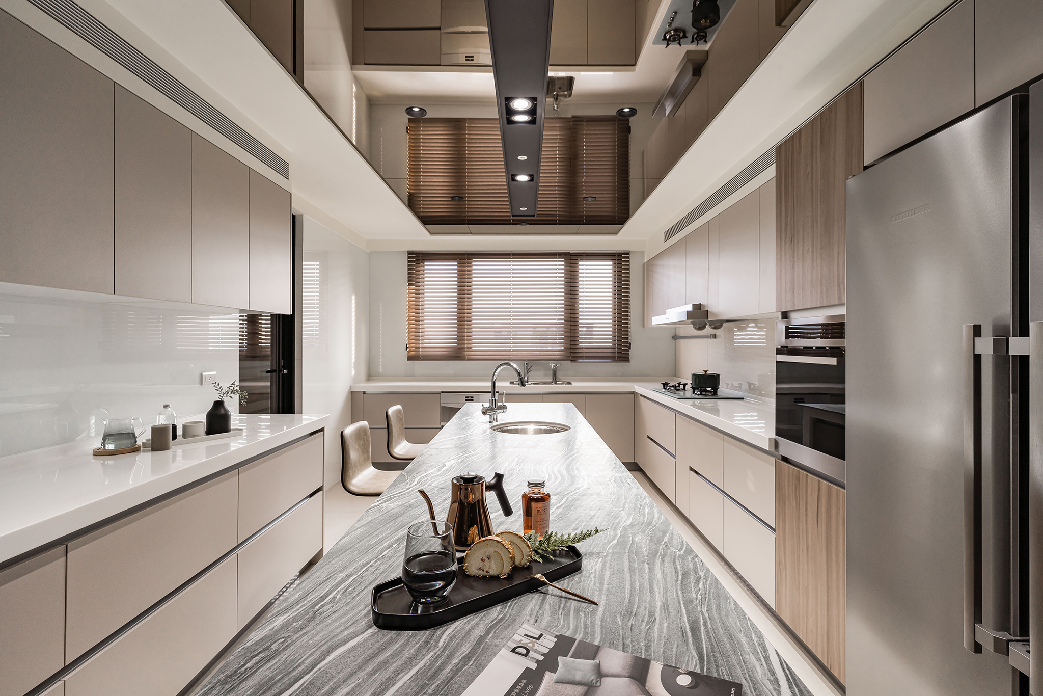 耐麗石中島設計案例：長型耐麗石（Neolith）紋理中島坐落於廚房中心，搭配鏡面天花板延伸空間感，與兩側對稱的奶茶色系櫥櫃、木質元素及百葉窗光影交織，打造出極具通透感與現代機能美學的專業餐廚空間。