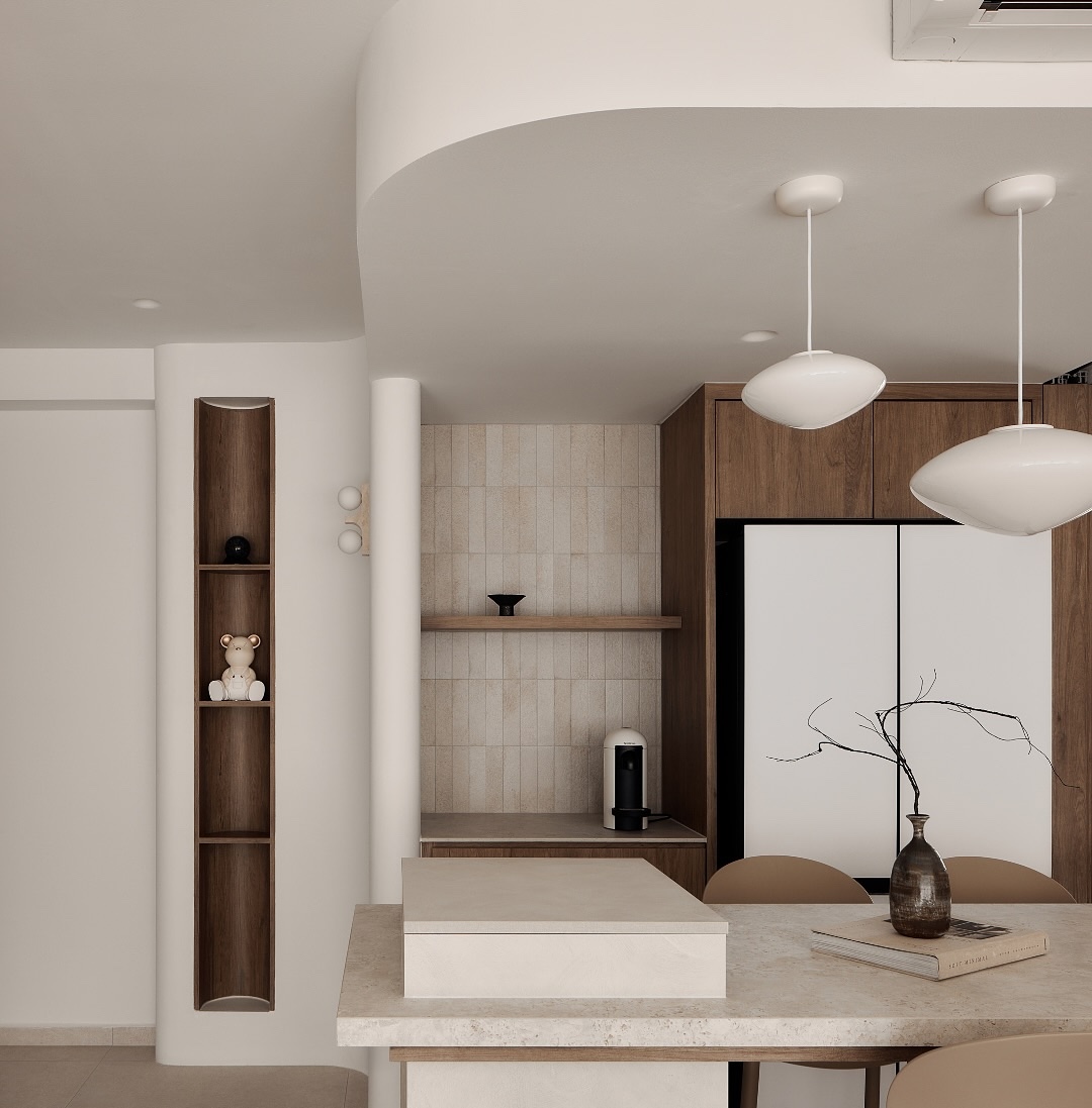 奶油色石材中島檯面搭配嵌入式分層設計，結合溫潤的木質收納櫃與圓潤的白色飛碟造型吊燈，在優雅的弧形天花板與內嵌式裝飾壁龕襯托下，營造出寧靜且具藝術感的生活層次。